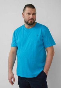 Kurzärmliges, rundhalsiges T-Shirt aus leuchtend blauem Stoff. Verfügt über eine dezente Textur und ein kleines Logo auf der Brust. Keine Muster oder Akzente.