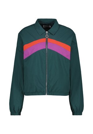 Veste verte raccourcie avec une fermeture éclair frontale, présentant des rayures diagonales orange et violettes sur la poitrine et des poignets élastiques aux manches.