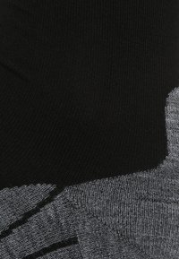 Calcetines en negro y gris con una textura acanalada, que presentan un patrón diagonal creado por hilos en negro sólido y gris jaspeado.