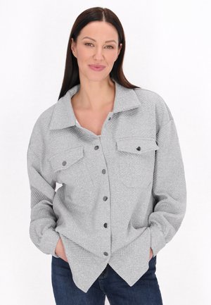 Grijze button-up shirt met een gestructureerde kraag, twee borstzakken en een textuurstof. Gestyled met donkere jeans, die een ontspannen pasvorm tonen.