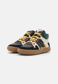 Hoge sneakers van zwart leer en suede, met gele veters, witte en groene accenten, en een gumrubberen zool.