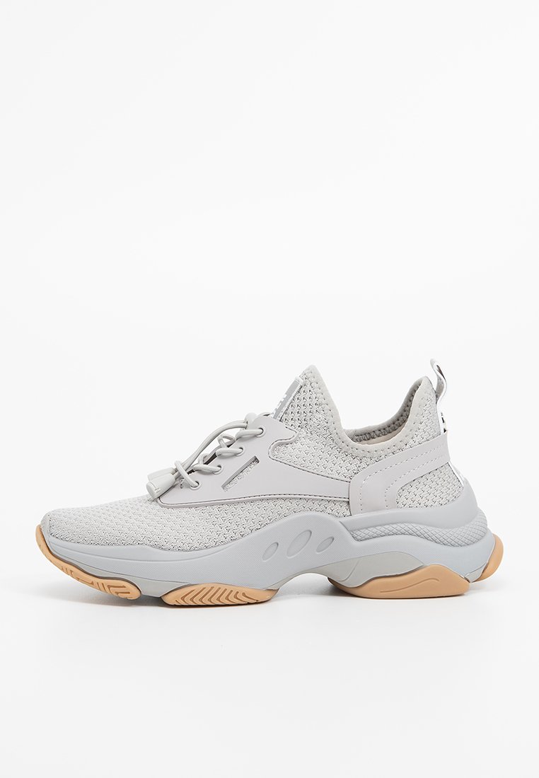 Zapatillas deportivas de color gris claro con parte superior de malla, acentos texturizados, cordones elásticos y una suela acolchada en blanco y beige.