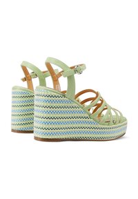 Sandali con zeppa in pelle verde, con una piattaforma intrecciata multicolore, caratterizzati da fasce incrociate e una cinghia alla caviglia regolabile.