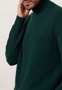 Grön stickad polotröja i mjukt material, med slim fit och ribbade ärmslut. Slät yta med en klassisk design.