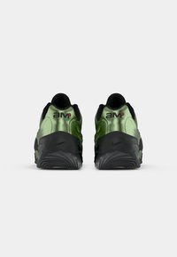 Green and black sneakers feature a glossy, curved upper, textured sole, and prominent branding on the heel and side.