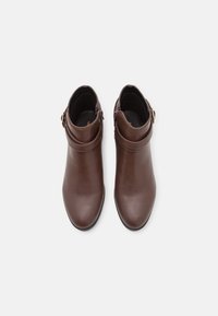 Bottines en cuir marron à texture lisse, avec un bout arrondi, une fermeture éclair latérale et une sangle à boucle autour de la cheville.