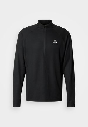 Pulover negru cu mâneci lungi și fermoar până la jumătatea gulerului. Realizat dintr-un material texturat, cu un logo triunghiular alb pe piept în partea stângă.