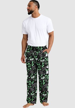 Schwarze Herren-Pyjama-Hosen mit grünen verspielten Mustern, aus weichem Stoff gefertigt. Sie verfügen über einen elastischen Bund und Seitentaschen. Kombiniert mit einem weißen T-Shirt.