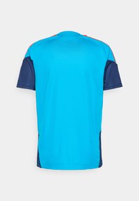 T-shirt αθλητικής κοπής με κοντό μανίκι σε φωτεινό τυρκουάζ ύφασμα, με ναυτική χρωματική απόχρωση στις μανσέτες και στα πλάγια, και κόκκινες λεπτομέρειες στους ώμους.