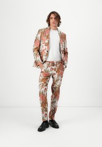 Blomstrete drakt laget av lett stoff, med store rosa og oransje blomster med grønne blader, kombinert med en enkel hvit t-skjorte, og svarte sko.