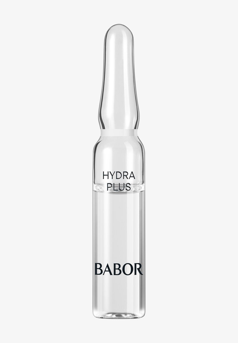 Vial en verre clair avec un sommet effilé, étiqueté "HYDRA PLUS" et "BABOR" en texte noir. Le vial contient un liquide, montrant sa transparence.