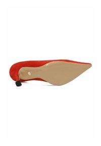 Zapato de tacón alto de ante rojo con puntera afilada y suela beige. Presenta un tacón curvado con un pequeño detalle de tapa negra.