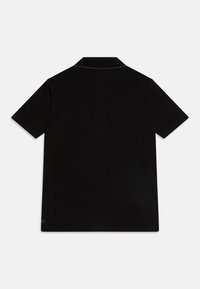 Polo noir à manches courtes, fabriqué en tissu lisse, avec un col classique, un design minimaliste et des bords nets.