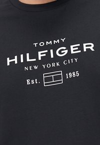 Czarna bawełniana koszulka z białym napisem "TOMMY HILFIGER NEW YORK CITY Est. 1985" z detalem w postaci logo w ramce pod napisem.