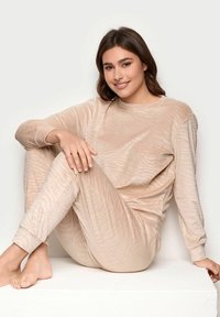 Beżowy zestaw odzieży domowej wykonany z miękkiego, strukturalnego materiału z delikatnym wzorem w paski. Długie rękawy i dopasowane mankiety podkreślają luźny krój.