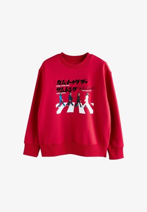 Sudadera roja con cuello redondo y mangas largas. Estampado gráfico de cuatro figuras cruzando una franja blanca con texto en negro y en japonés.