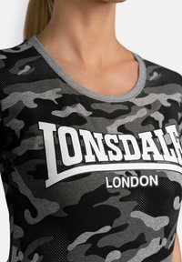 Black and grey camouflaged T-shirt in soft fabric, featuring a rounded neckline and bold white "Lonsdale London" logo on front.