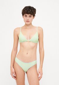 Svetlozelena bikini set, ki vsebuje trikotno bralette s tankimi naramnicami in ujemajočimi se nizkimi hlačkami, okrašenimi z diskretnim cvetličnim vzorcem.