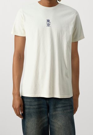 Kortærmet hvid t-shirt i bomuld med blåt japansk tekstmotiv i midten, rund halsudskæring og afslappet pasform. Glat tekstur.