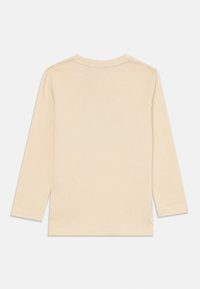 Langermet skjorte i lys beige bomull. Har rund hals, rett kant og minimalistisk design uten synlige mønstre eller detaljer.