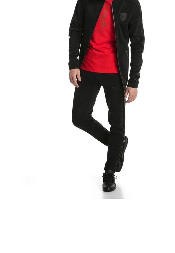 Veste et pantalon de sport noirs avec un t-shirt rouge. La veste possède une fermeture éclair devant et un logo sur la poitrine. Tissu lisse, coupe ajustée et accents minimaux.