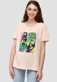 Vaaleanpunainen puuvillapaita, jossa on värikäs sarjakuvatyylinen grafiikka hahmoista neliömäisessä muotoilussa vihreillä, vaaleanpunaisilla ja keltaisilla yksityiskohdilla.