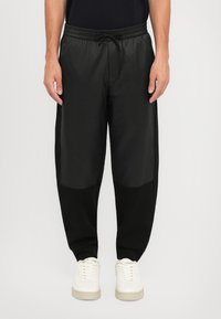 Sorte joggebukser med en lett, glatt tekstur; elastisk midjebånd med snor; tettsittende passform, med kontrasterende svarte paneler.