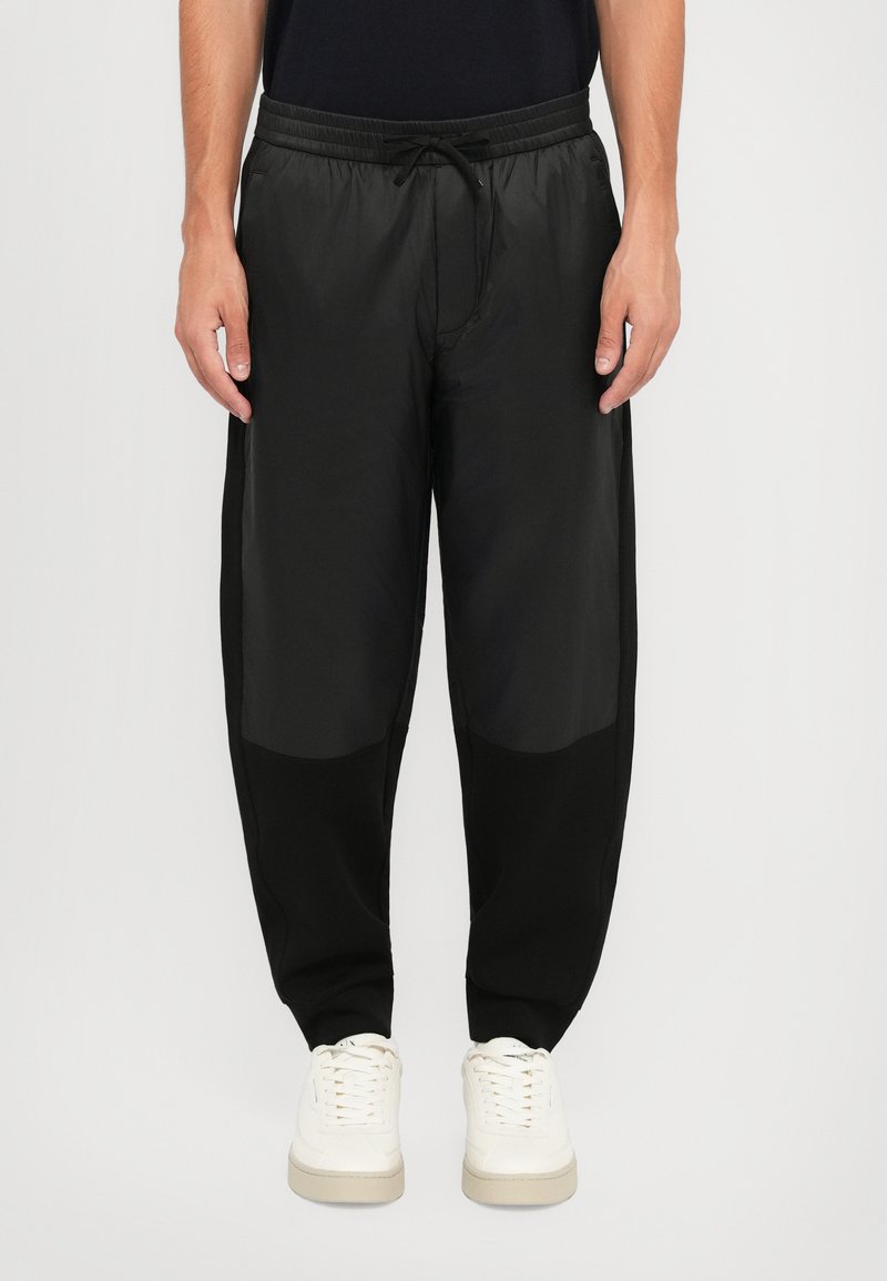 Sorte joggebukser med en lett, glatt tekstur; elastisk midjebånd med snor; tettsittende passform, med kontrasterende svarte paneler.