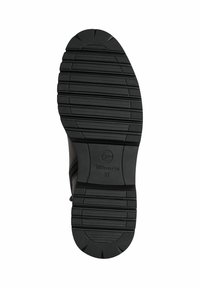 Semelle de chaussure en caoutchouc noir avec un motif de bande de roulement texturé, présentant des rainures pour l'adhérence et un logo circulaire avec "37" embossé au centre.