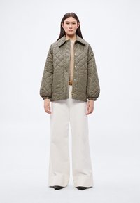 Prošívaná bunda s motivem psa zub, s límečkem, zapínáním na knoflíky a elastickými manžetami, doplněná o bílé kalhoty s širokými nohavicemi.