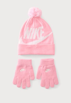 Roosa kootud müts pom-pommi ja sobivate kinnastega, kõik valge Nike logoga ja swooshiga heledal taustal.