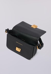 Borsa a tracolla in pelle nera con chiusura in oro, con il marchio "Gentle Society" impresso, flap aperto che mostra l'interno con il nome del brand "Trussardi."