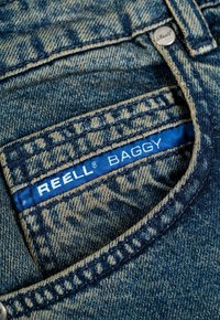 Helle blaue Denim-Jeans im baggy Schnitt. Verfügt über ein blaues Etikett mit der Aufschrift "REELL BAGGY" und zeigt kontrastierende Steppnähte.