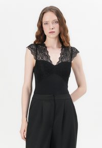 Black bodysuit with lace cap sleeves and a v-neckline. Fitted design with a smooth texture, contrasted by intricate lace detailing.