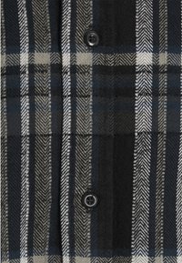 Rutigt skjorta i marinblått, grått och vitt. Tillverkad av mjukt tyg med ett fiskbensmönster och en svart knapp.