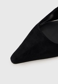 Crna zamština visoka potpetica s oštrim vrhom i glatkim unutarnjim oblogom. Nema vidljivih metalnih dijelova ili uzoraka. Elegantna silueta.