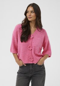 Rosa gestrickte Kurzarm-Strickjacke mit drei knopfartigen Rosen, geripptem Saum und V-Ausschnitt.