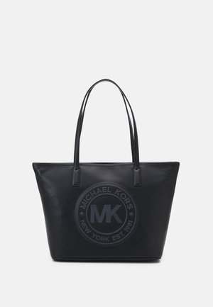 Black leather tote bag with structured shape, featuring a large circular logo on the front, slim shoulder straps, and textured surface.