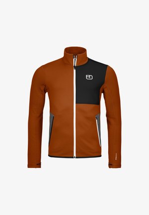 Two-tone softshell jacket in burnt orange and black, with gray accents. Features a high collar, zip closure, and zippered side pockets.