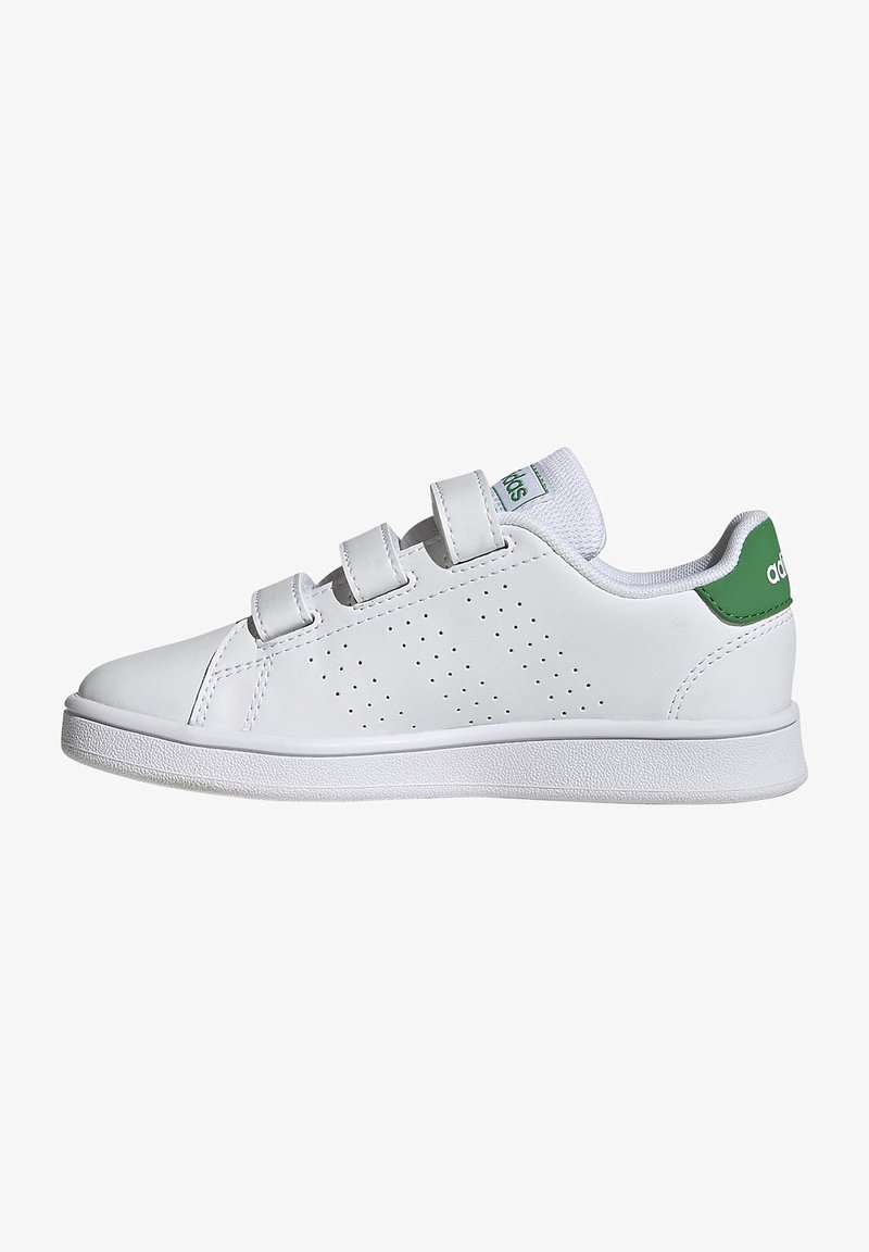 Zapatilla de cuero blanco con detalles perforados, correas de velcro y un acento verde en el talón. Incluye una suela de goma blanca texturizada.