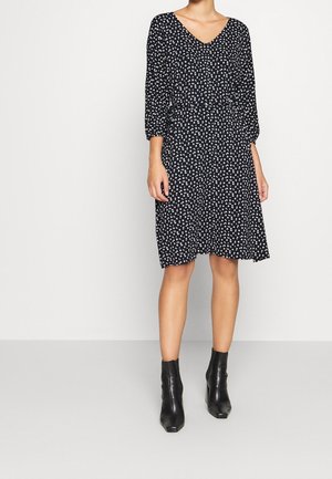 Zwarte bloemenjurk met een V-hals, driekwartmouwen en een getailleerde taille, voorzien van een uitlopende rok en subtiele witte bloemenpatronen.