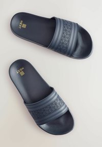 Infradito blu navy con cinturini testurizzati; presenta un motivo geometrico e un materiale in gomma liscio; logo dorato visibile sulla soletta.