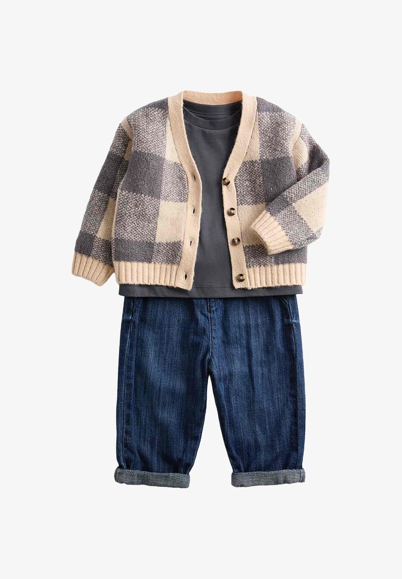 Creme- und grauen karierter Cardigan mit sechs Knöpfen, kombiniert mit einem dunkelgrauen T-Shirt und hochgekrempelten dunkelblauen Jeans.