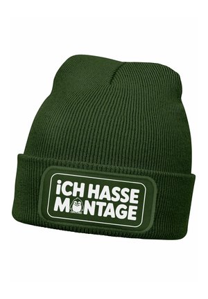 Green knitted beanie with a folded cuff, featuring a rectangular patch displaying white text “Ich hasse Montage” and a cartoon character.