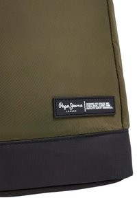 Olīvu zaļš neilona maciņš ar melnu apakšējo paneli un tekstila marķējumu, kurā baltā krāsā ir uzraksts "Pepe Jeans London". Gluda tekstūra, minimālisma dizains.