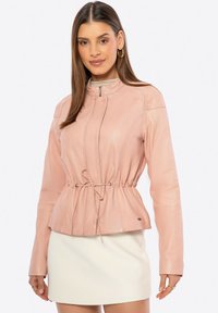 Giacca in pelle rosa chiaro con colletto alto, zip frontale e vita regolabile con cordino. Texture liscia e design aderente con maniche lunghe.