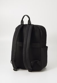 Černý batoh s polstrovanými, síťovanými ramenními popruhy a horním uchem. Vyznačuje se moderním designem a bočními kapsami pro úložný prostor. Texturovaná tkanina.