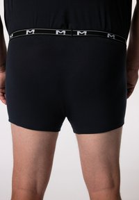Černé boxerky s těsným střihem a elastickým pasem. Pas zdobí opakující se vzor bílého loga. Hladká textura látky.