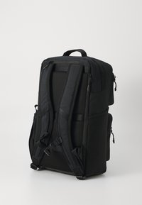 Sac à dos noir avec des bretelles rembourrées, une poignée supérieure et plusieurs compartiments zippés. Fabriqué en tissu durable avec une finition texturée.
