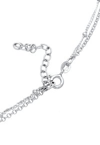 Silver metal chain bracelet with a clasp, featuring varying link sizes and a round tag marked "925," indicating sterling silver content.